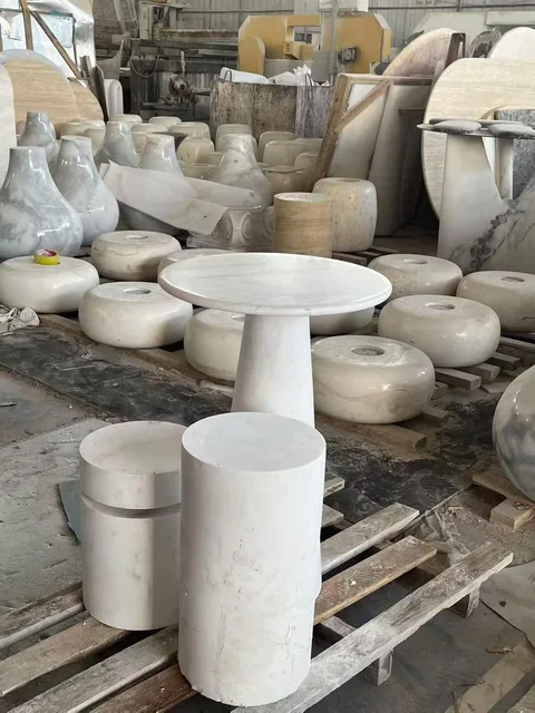 white stone side table, with a central pedestal base and fine veining, in a workshop