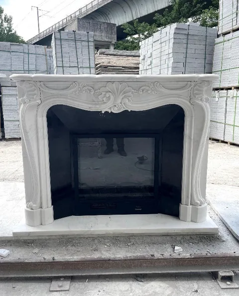 White Volakas marble fireplace surround, with fine veining, shown from a frontal view with workshop equipment nearby