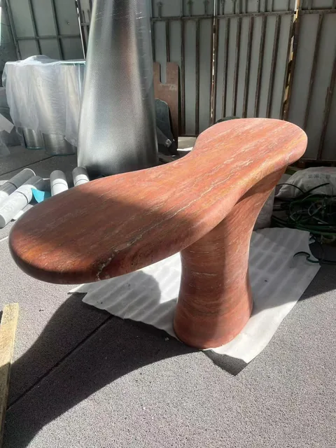 rose-red stone bench, with a curved seating plan and fine veining, in a workshop
