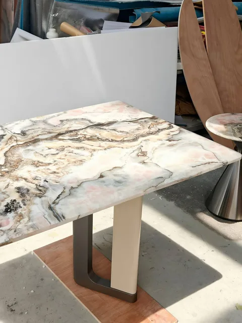 white stone dining table, with bold veining and a reflective finish, in a workshop