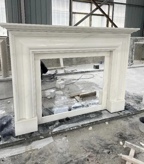 White Volakas marble fireplace surround, shown from an angled view with workshop equipment nearby