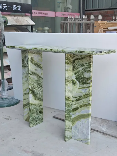 green stone console table, with twin supporting bases and bold veining, in a workshop
