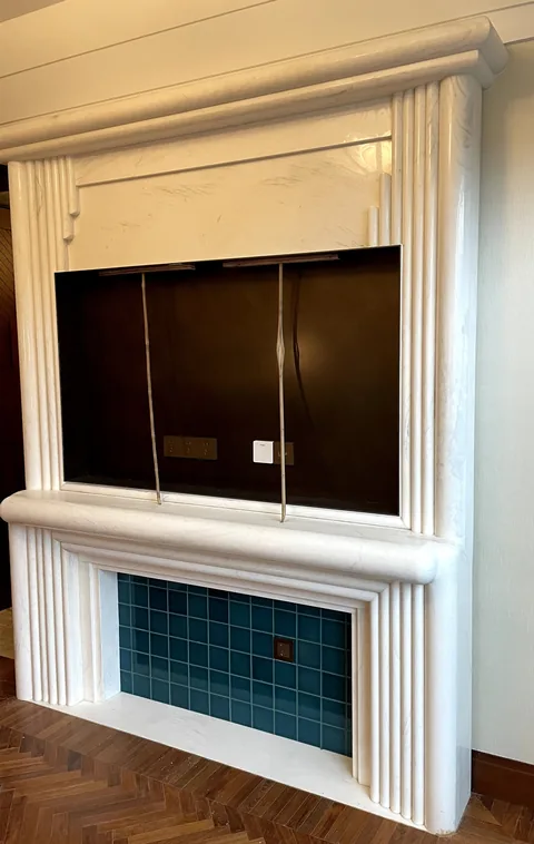 White Volakas marble fireplace surround, with fine veining and a reflective finish, in a furnished room