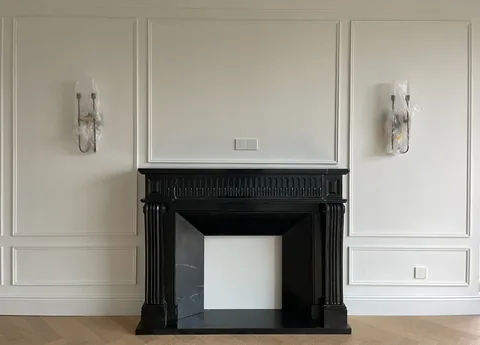 White Volakas marble fireplace surround, with a straight recessed opening and fine veining, in a furnished room