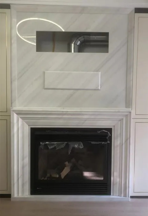 Arabescato Corchia marble fireplace surround, with stepped tiers and fine veining, in a furnished room