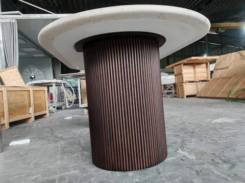 white stone dining table, with a central pedestal base and fine veining, in a workshop