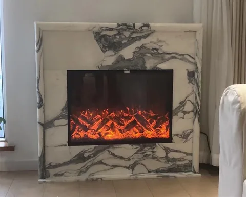 Arabescato Corchia marble fireplace surround, with a simple slab frame and bold veining, in a furnished room