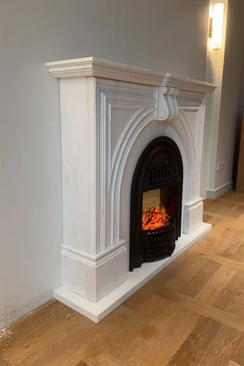 White Volakas marble fireplace surround, with fine veining, shown from an angled view with subtle pattern contrast