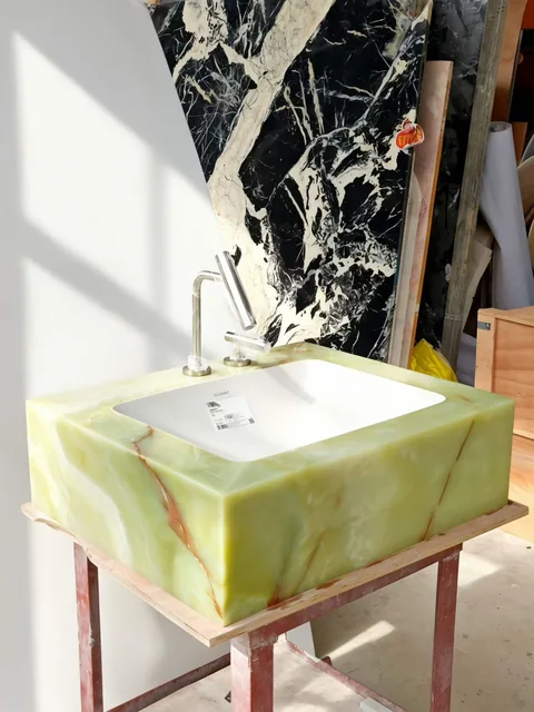 green stone sink, with a form carved from solid stone and bold veining, in a workshop