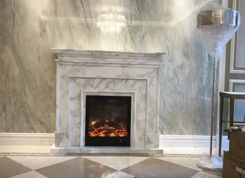 Arabescato Corchia marble fireplace surround, with stepped tiers and fine veining, in a furnished room