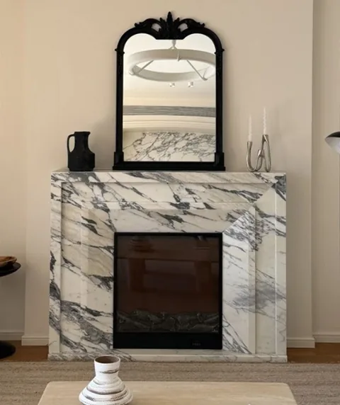 Arabescato Corchia marble fireplace surround, with bold veining and a reflective finish, in a furnished room