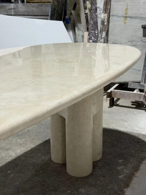 cream-beige stone dining table, with cloudy mottling and a reflective finish, in a workshop