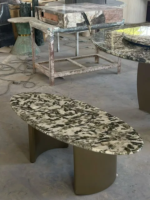 cream-beige stone coffee table, with twin supporting bases and angular breccia fragments, in a workshop