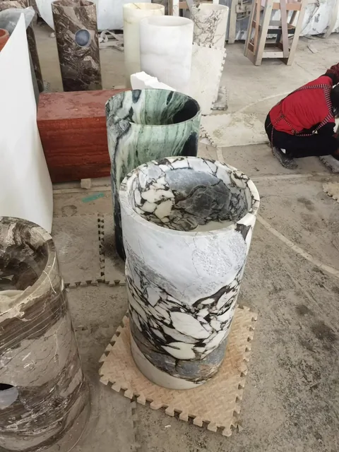 white stone sink, with a form carved from solid stone and bold veining, in a workshop