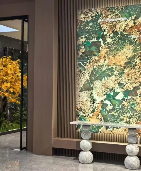 green stone wall feature, with large veined wall panels and angular breccia fragments, in a furnished room
