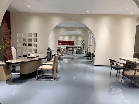 cream-beige stone dining table, with an irregular organic edge and cloudy mottling, in a showroom