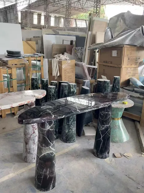black stone dining table, with twin supporting bases and bold veining, in a workshop