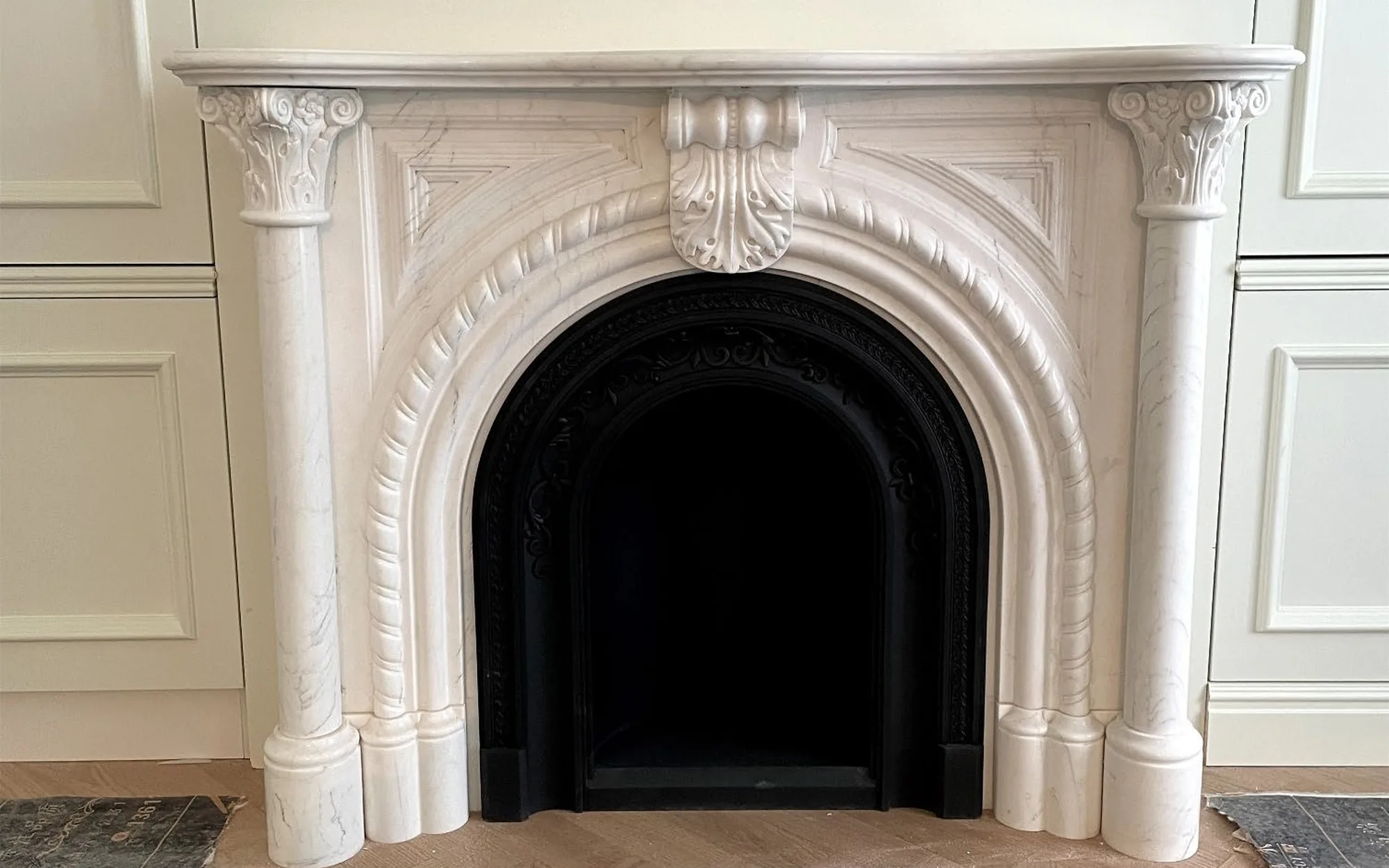 Ornate stone fireplace with a complete mantel and open firebox in a neutral room
