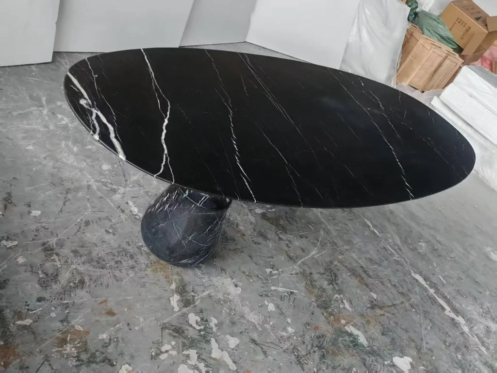 black stone dining table, with an oval top and bold veining, in a workshop