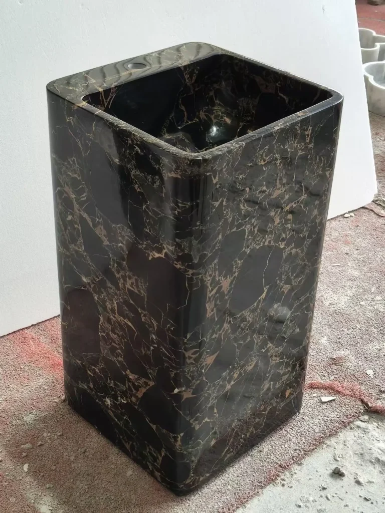 black stone sink, with a form carved from solid stone and bold veining, in a workshop