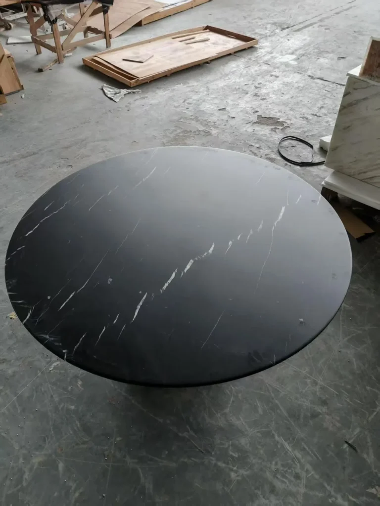 black stone dining table, with a round top and fine veining, in a workshop
