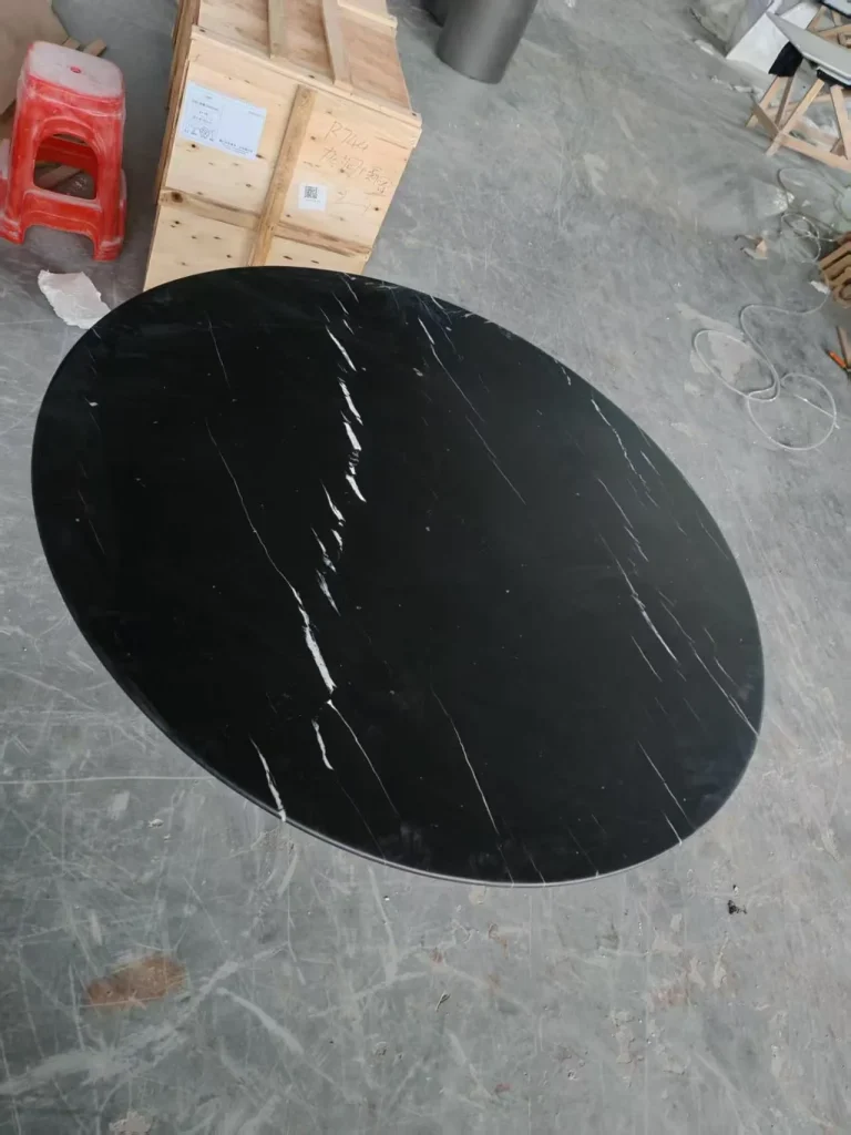 black stone dining table, with an oval top and fine veining, in a workshop