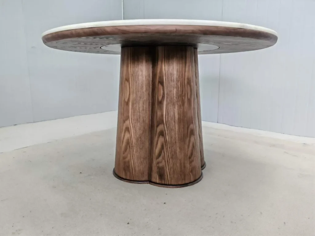 brown stone dining table, with a central pedestal base and a plain surface, against a pale background