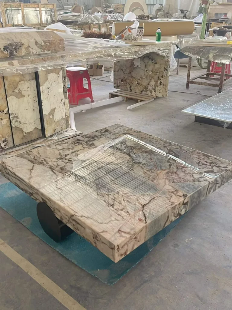 cream-beige stone coffee table, with bold veining and a reflective finish, in a workshop