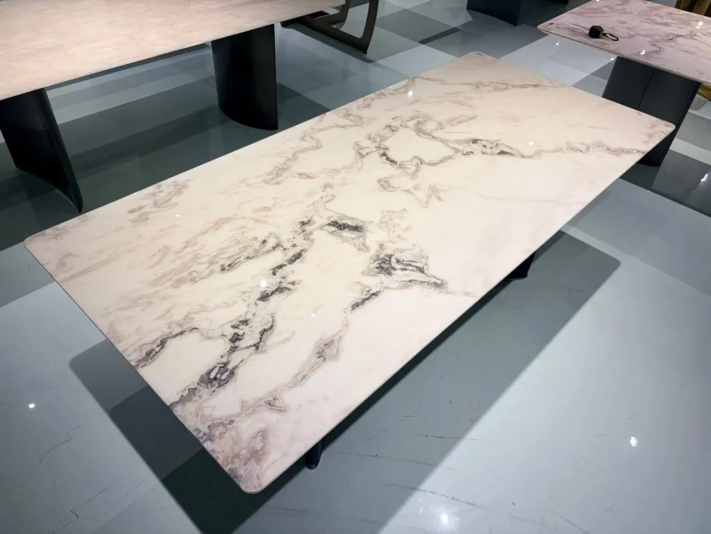 cream-beige stone dining table, with a rectangular top and bold veining, in a showroom