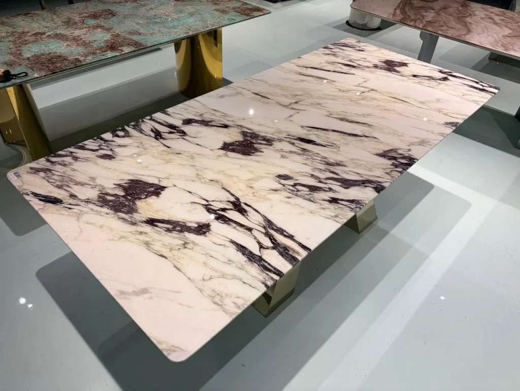 cream-beige stone dining table, with a rectangular top and bold veining, in a showroom