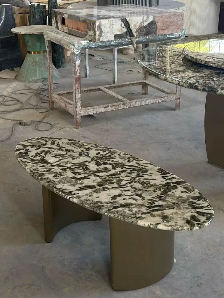 cream-beige stone coffee table, with twin supporting bases and angular breccia fragments, in a workshop