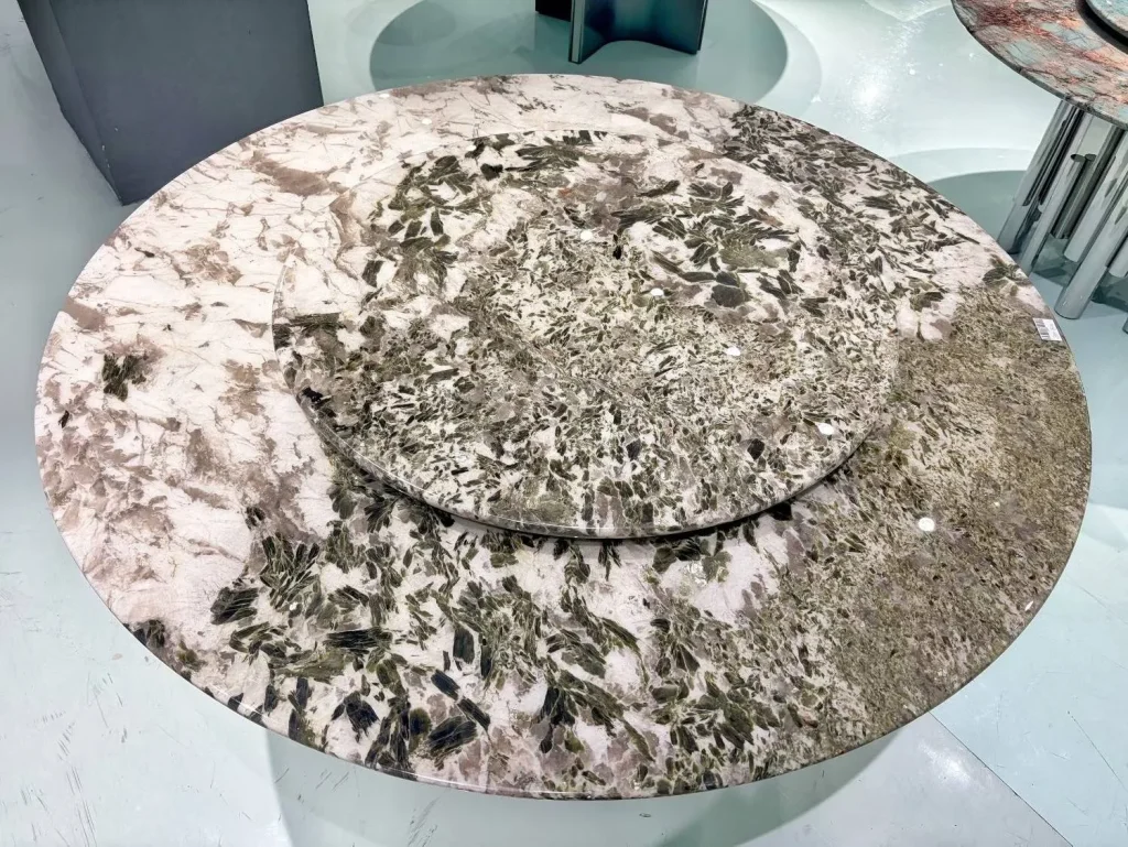 cream-beige stone dining table, with a round top and angular breccia fragments, in a showroom