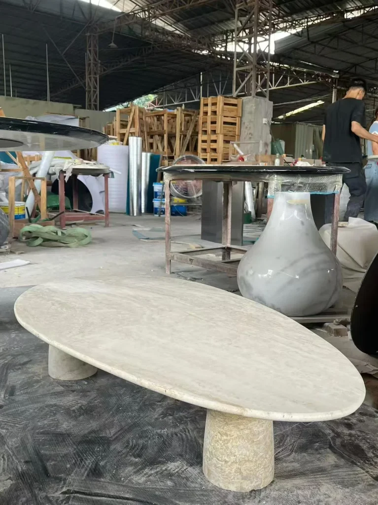 cream-beige stone coffee table, with twin supporting bases and cloudy mottling, in a workshop