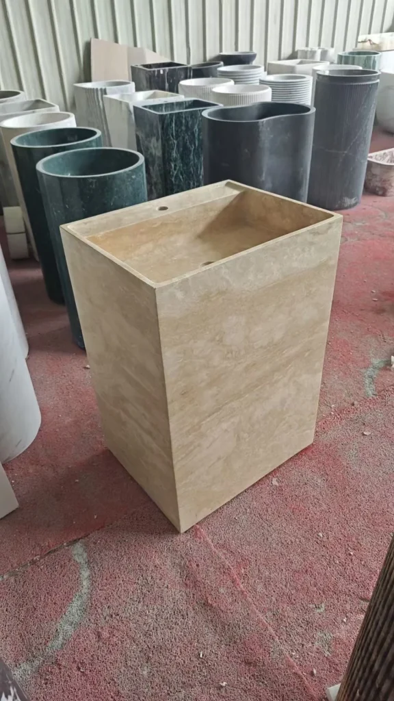 cream-beige stone sink, with a form carved from solid stone and cloudy mottling, in a workshop