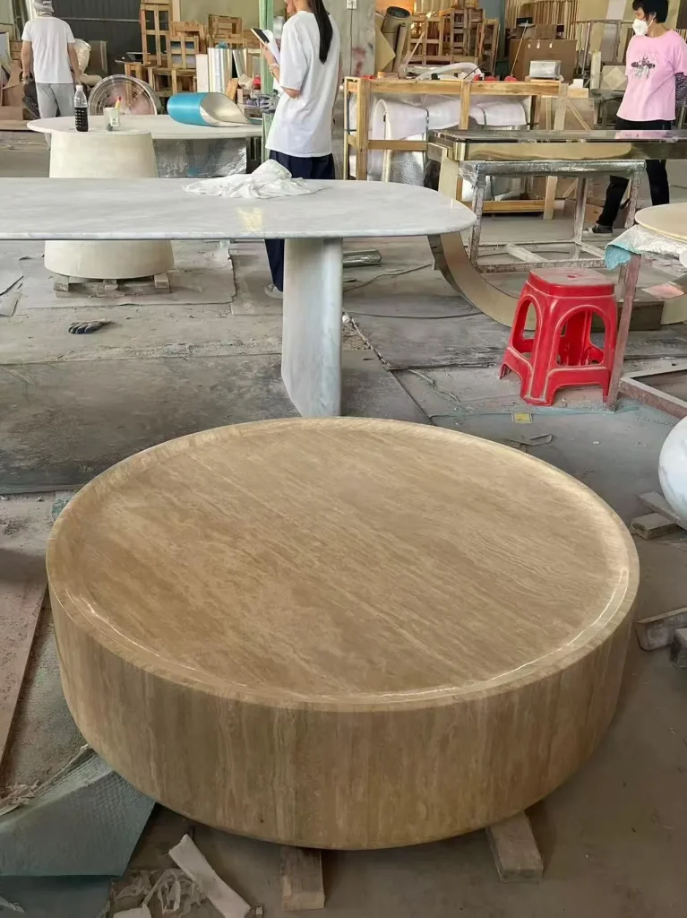 cream-beige stone coffee table, with fine veining and a reflective finish, in a workshop