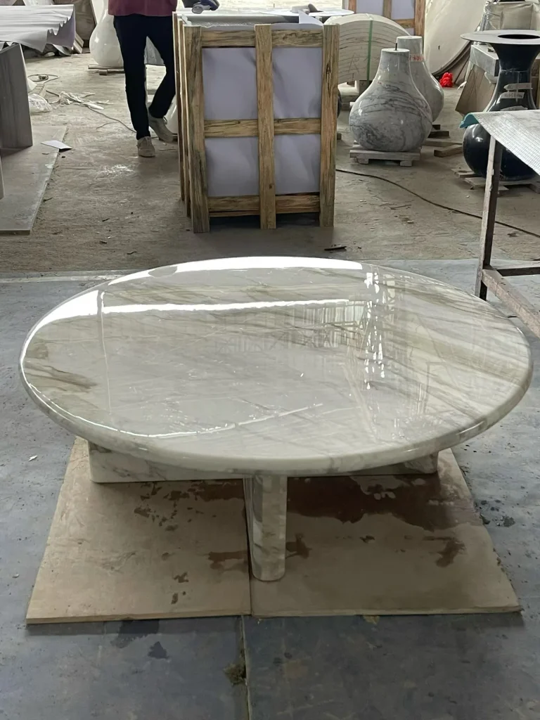 cream-beige stone coffee table, with fine veining and a reflective finish, in a workshop