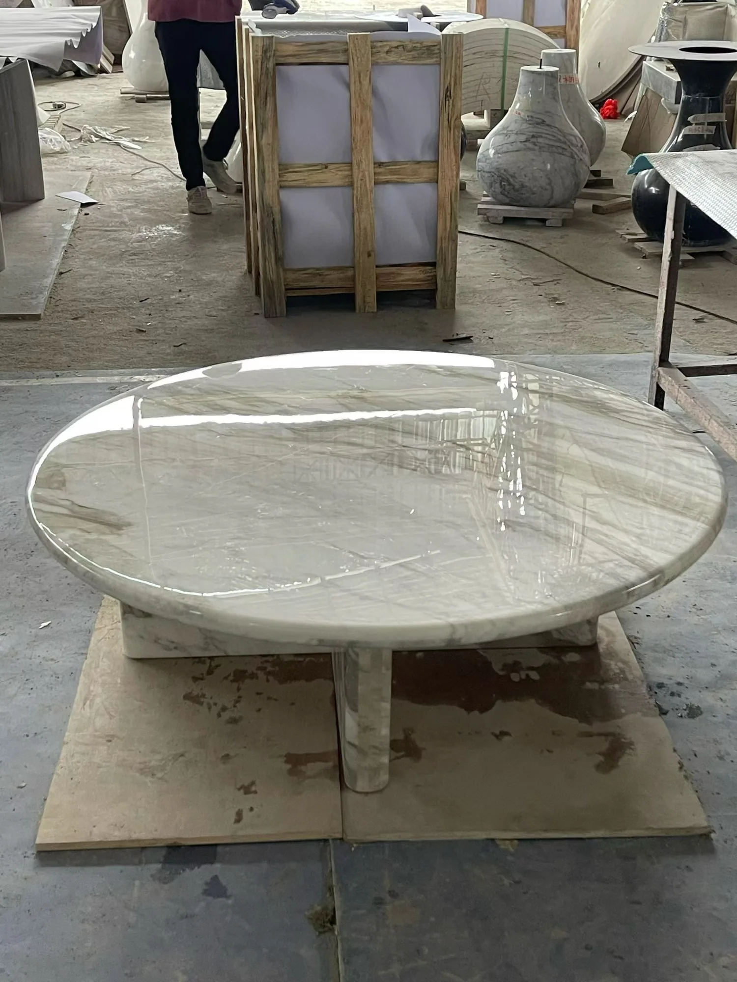 cream-beige stone coffee table, with fine veining and a reflective finish, in a workshop