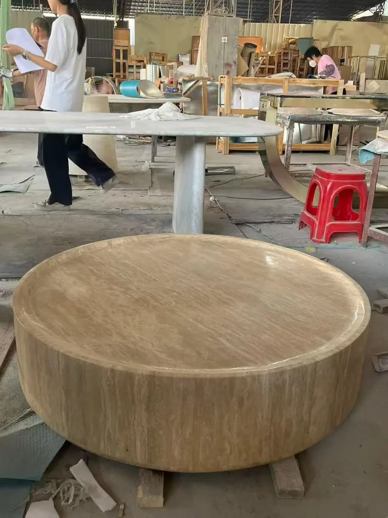 cream-beige stone coffee table, with fine veining and a reflective finish, in a workshop
