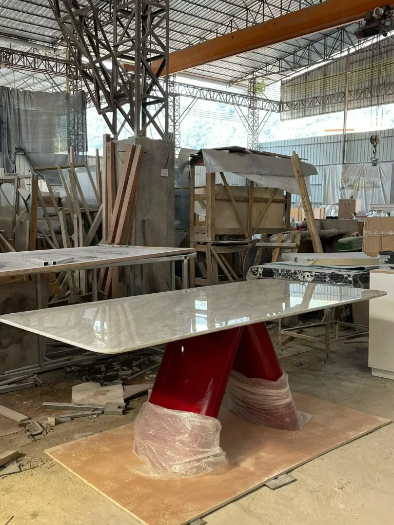 cream-beige stone dining table, with fine veining and a reflective finish, in a workshop