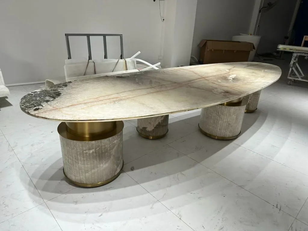 cream-beige stone dining table, with an oval top and fine veining, in a workshop