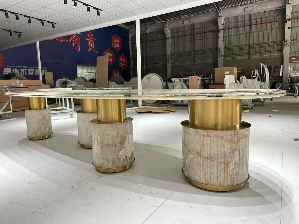 cream-beige stone dining table, with linear travertine grain and a reflective finish, in a workshop
