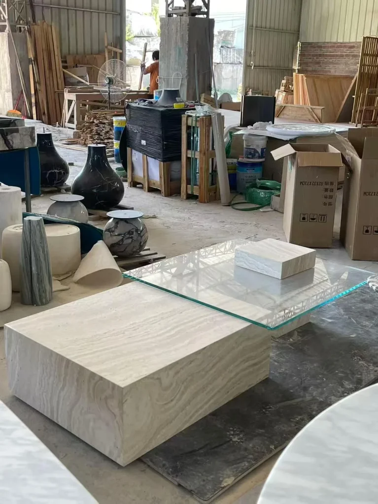 cream-beige stone coffee table, with a solid block base and wood-like grain, in a workshop