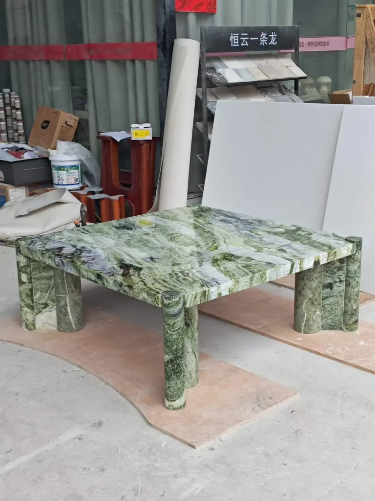 green stone coffee table, with bold veining and a reflective finish, in a workshop