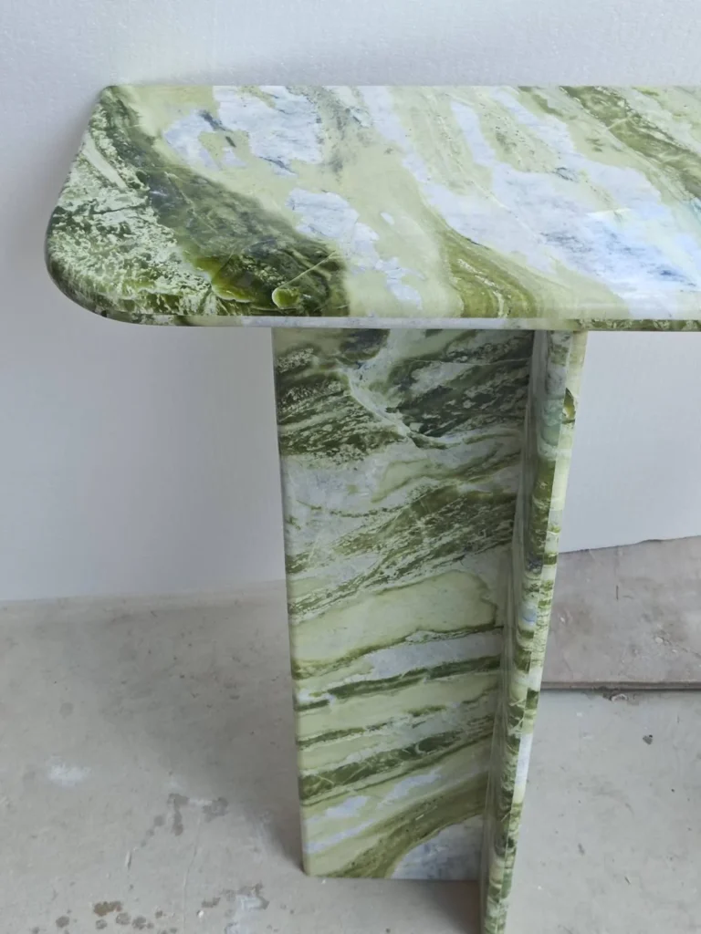 green stone console table, with bold veining and a reflective finish, against a pale background