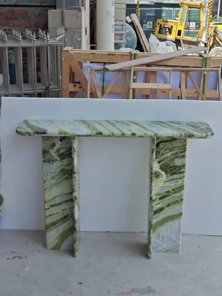 green stone console table, with twin supporting bases and bold veining, in a workshop