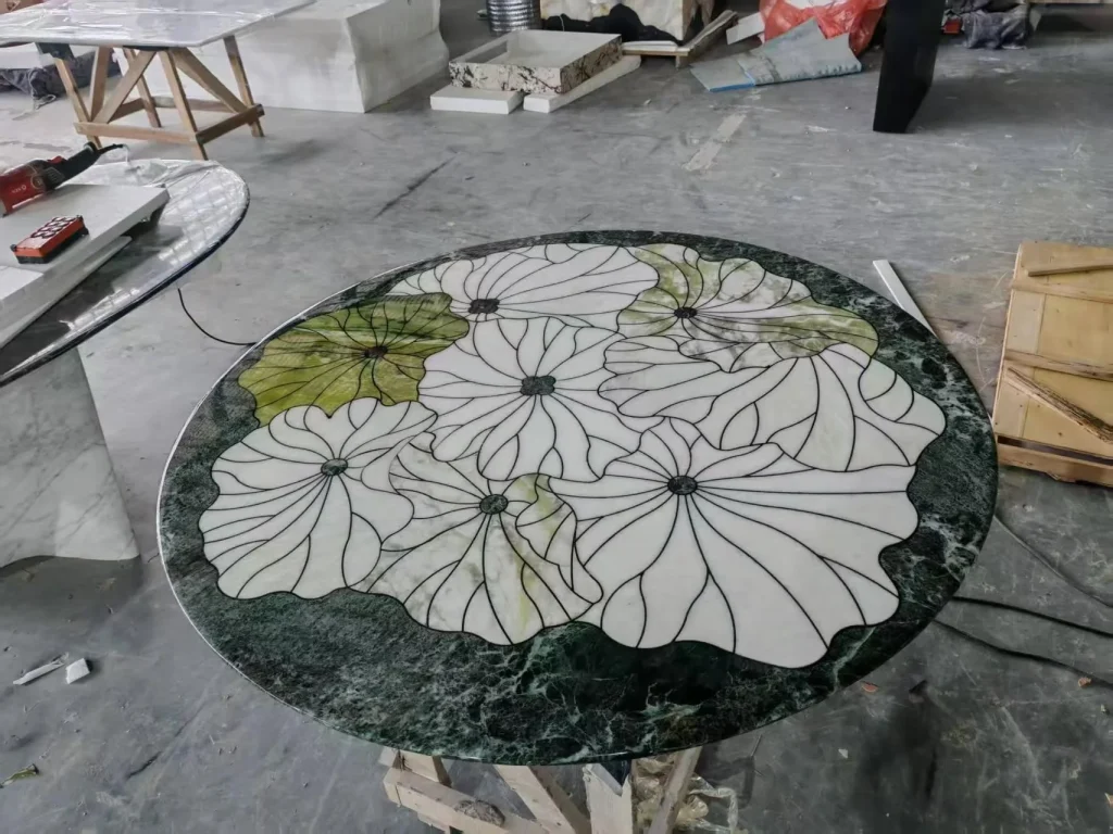 green stone dining table, with a round top and bold veining, in a workshop