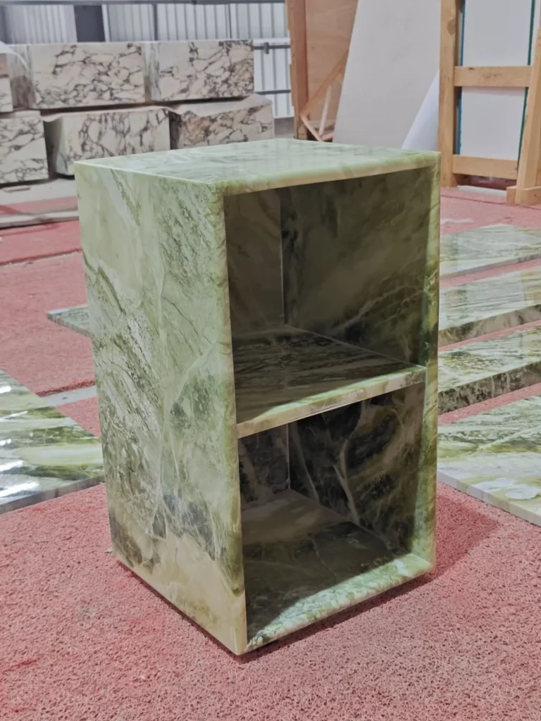 green stone side table, with bold veining and a reflective finish, in a workshop