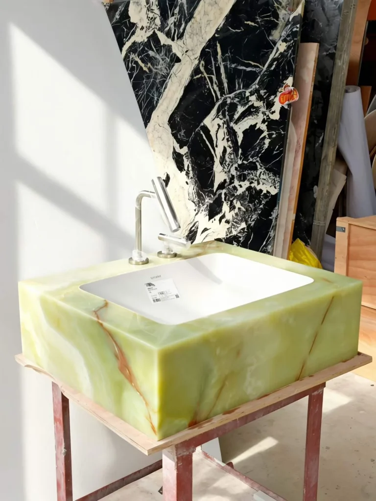 green stone sink, with a form carved from solid stone and bold veining, in a workshop