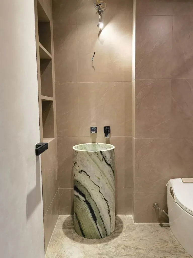 green stone sink, with a stone pedestal and bold veining, in a furnished room