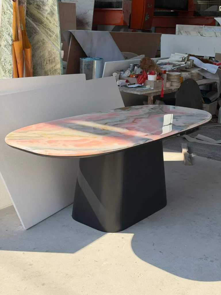 rose-red stone dining table, with cloudy mottling and a reflective finish, in a workshop